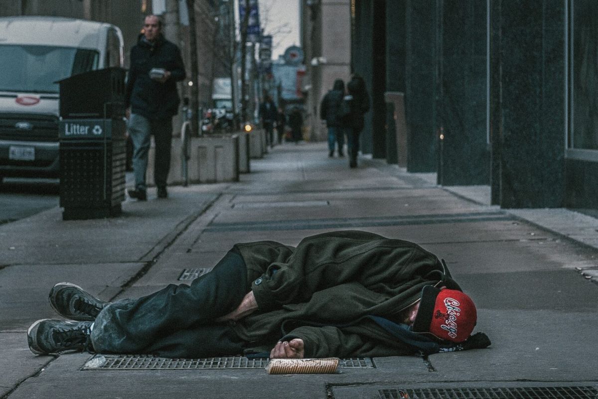 A stock photo of a homeless man lying in the middle of a street.