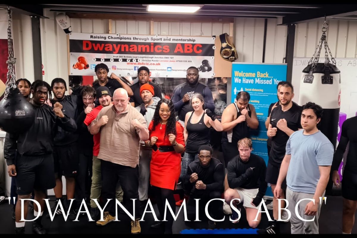 The members of local Brixton boxing club, Dwaynamics ABC, pose for a photo alongside members of Gallowglass Security in the gym with their fists up.