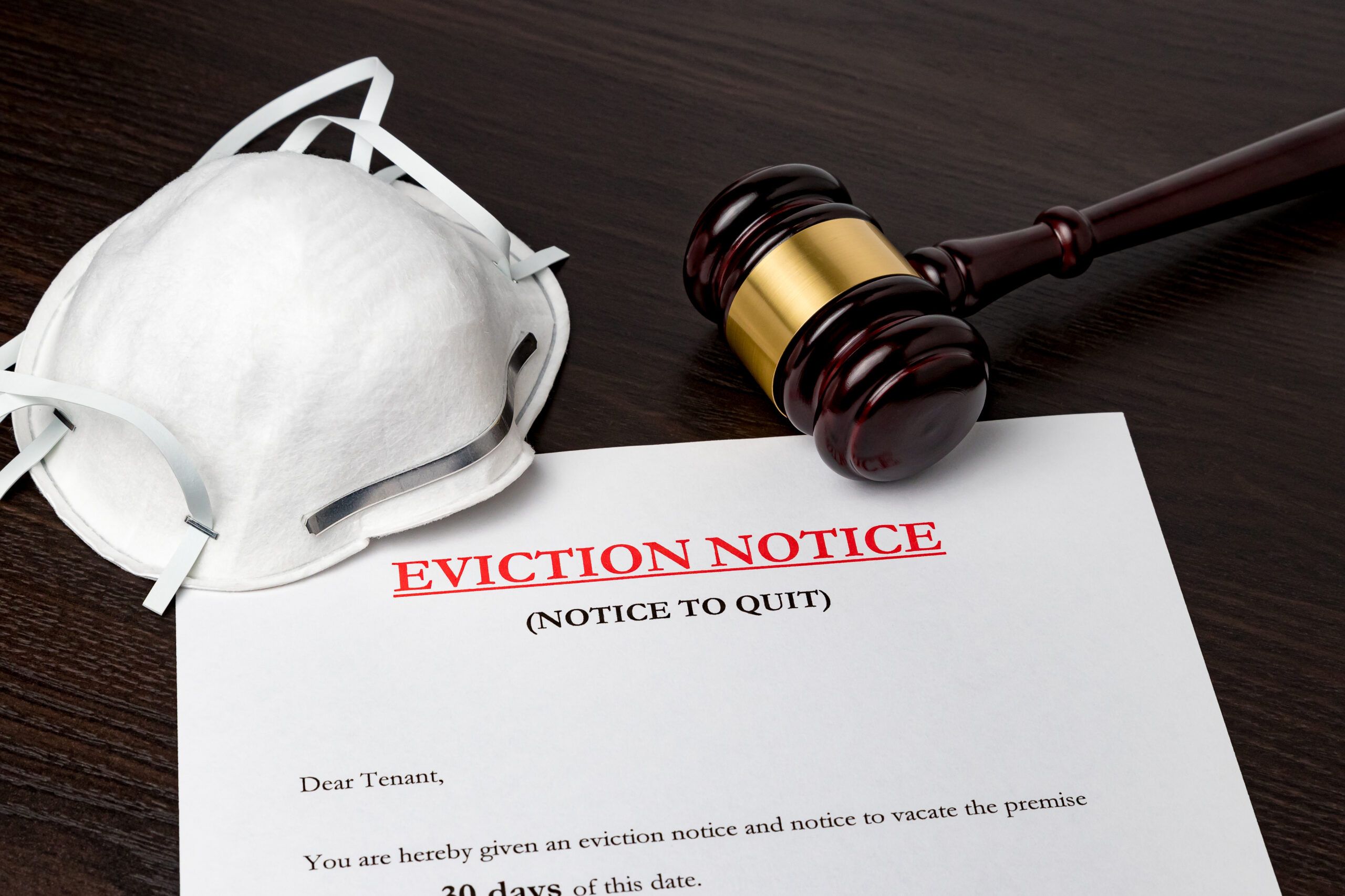 A stock photograph of an eviction notice next to a gavel and a mask.