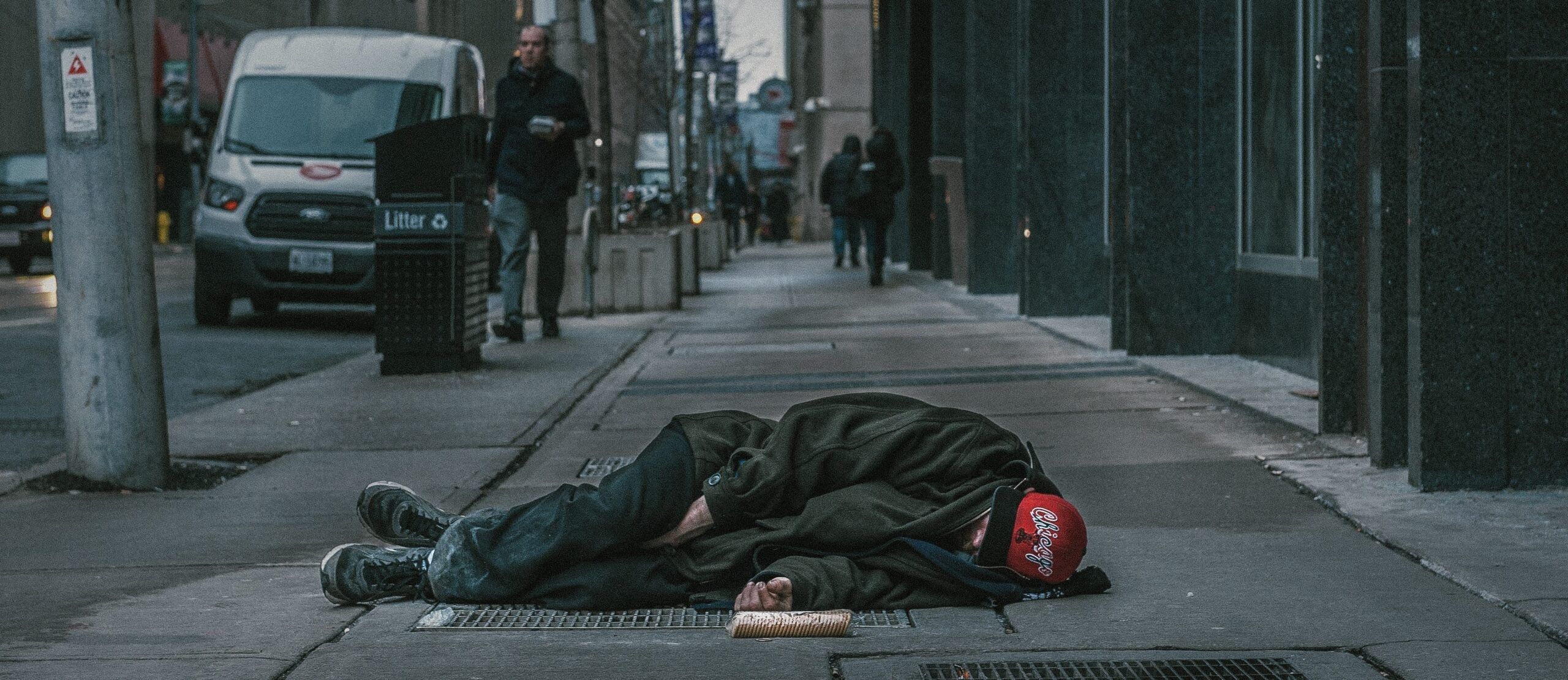 A stock photo of a homeless man lying in the middle of a street.