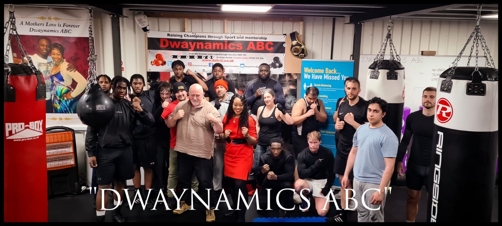 The members of local Brixton boxing club, Dwaynamics ABC, pose for a photo alongside members of Gallowglass Security in the gym with their fists up.